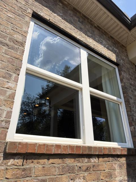 The same exterior window after cleaning, clear glass reflecting the sky